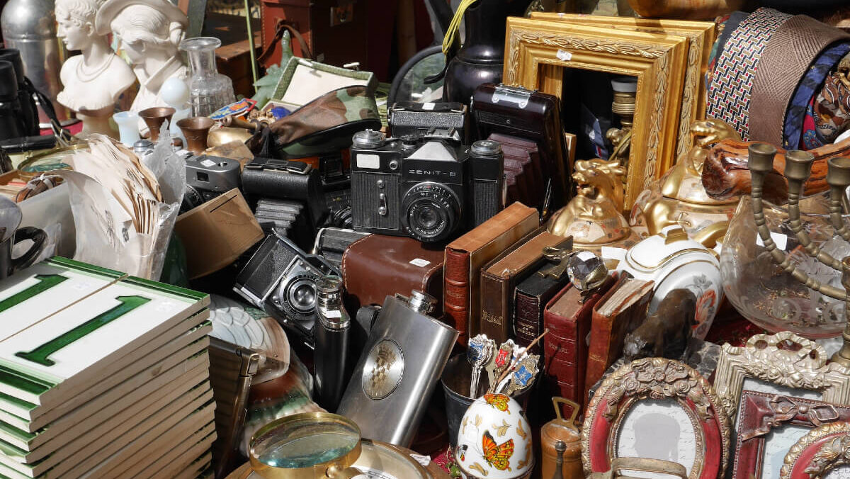 A stall at a flea market filled with items to sell, tiles, picture frames, bits and bobs.