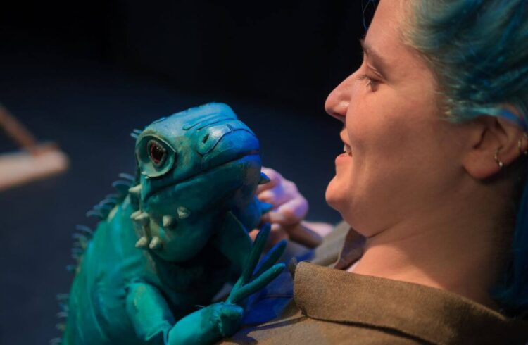 A woman holding a lizard puppet