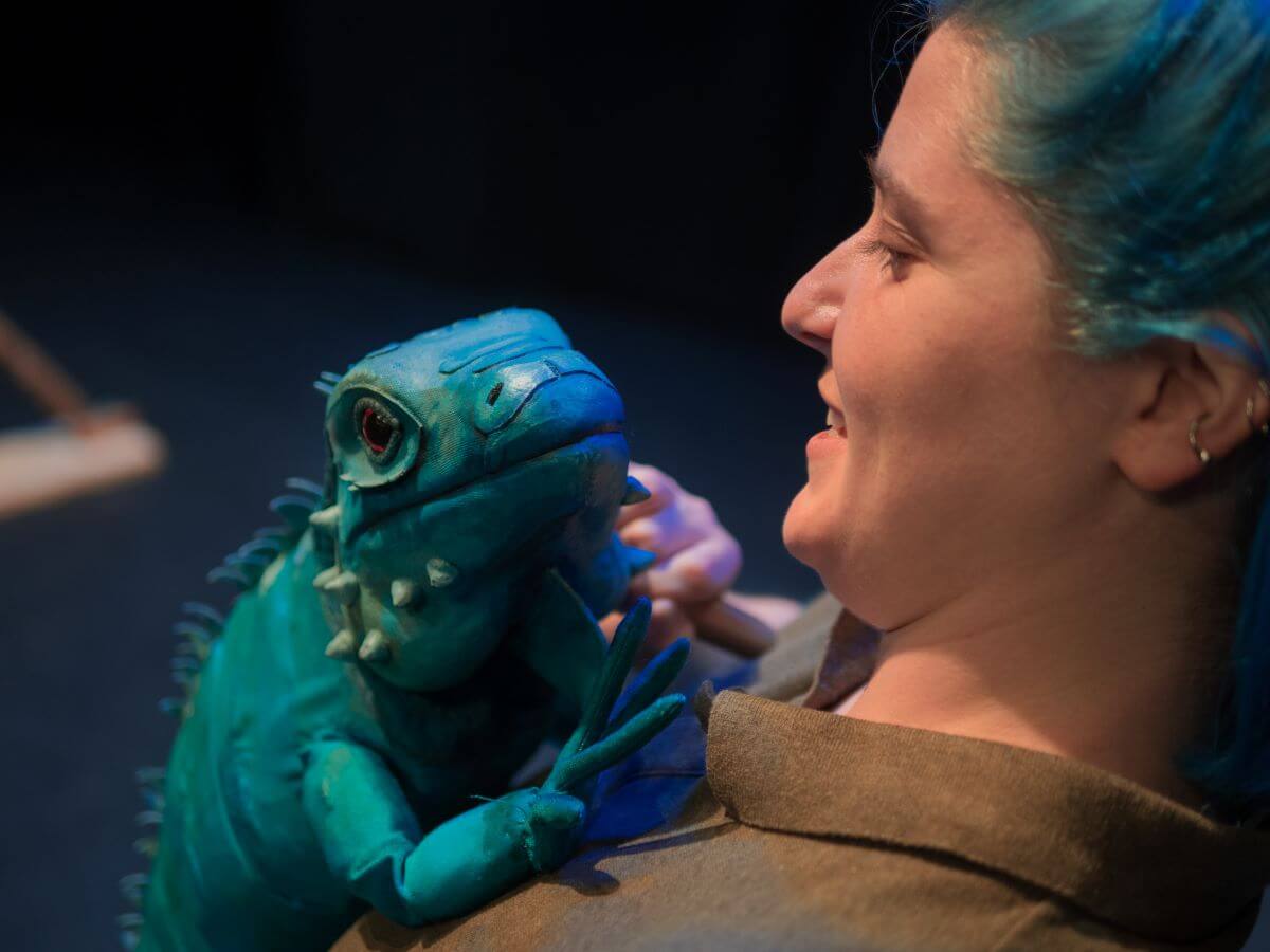 A woman holding a lizard puppet