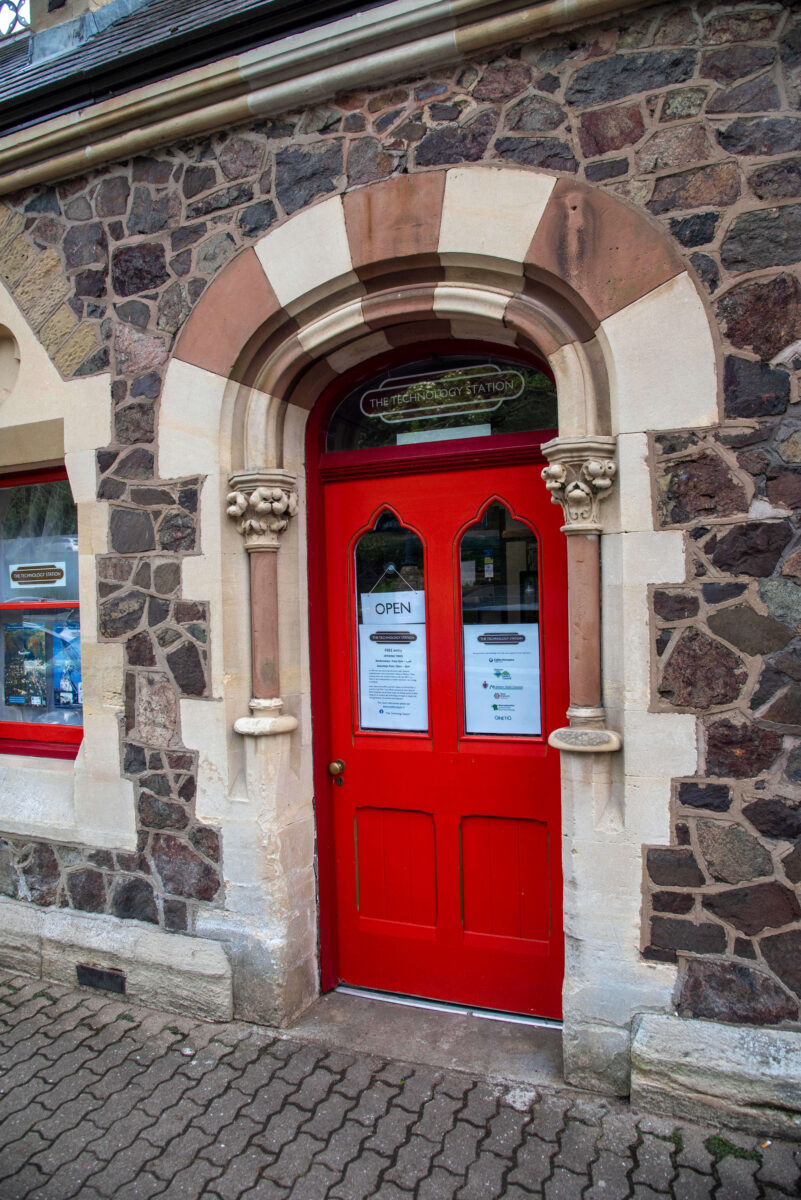 A red Victorian door set into a wall made of Malvern Stone
