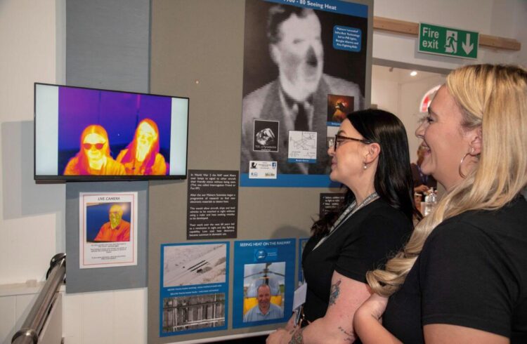 Two people look at a heat detecting screen in a museum