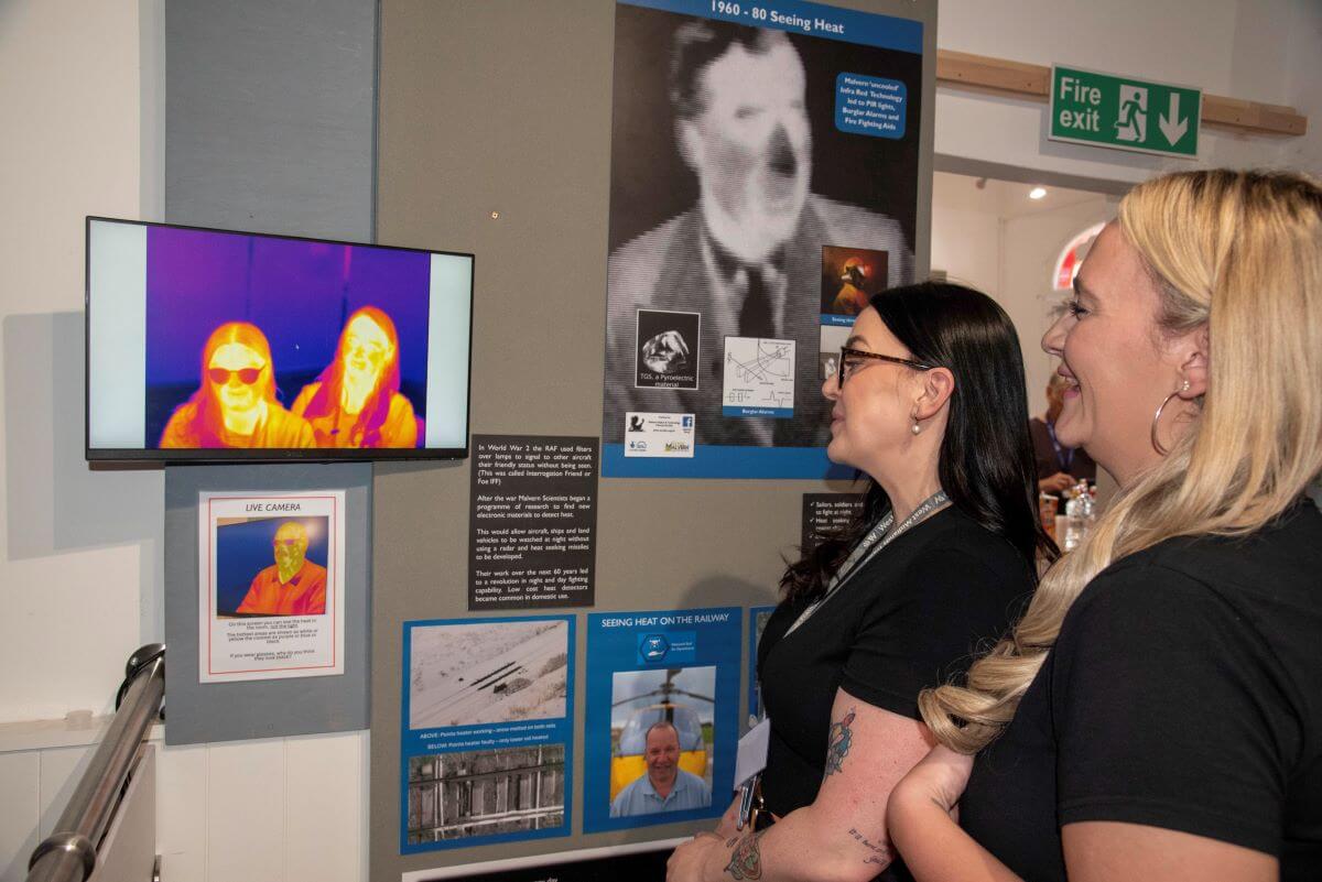 Two people look at a heat detecting screen in a museum