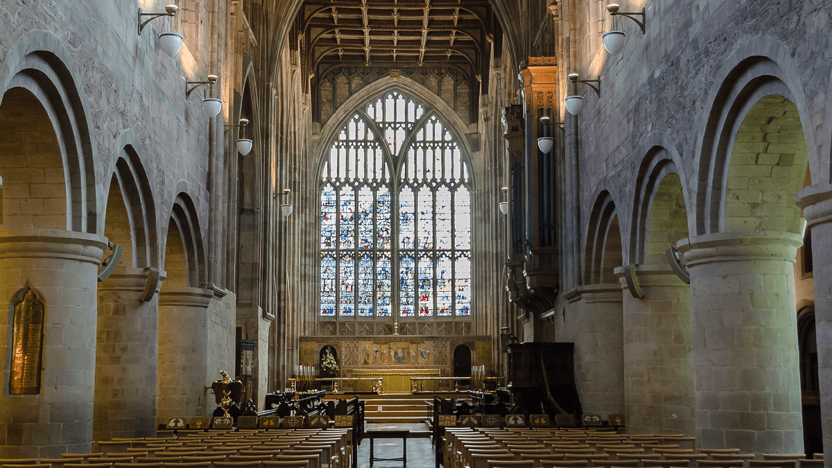 The interior of Great Malvern Priory with Norman pillars and large east window in stained glass