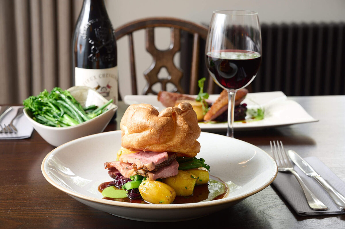 A roast dinner on a table with a glass of wine