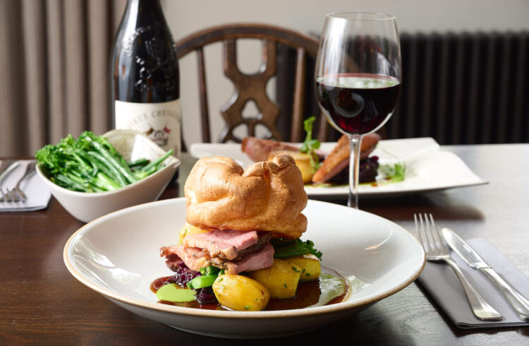 A roast dinner on a table with a glass of wine