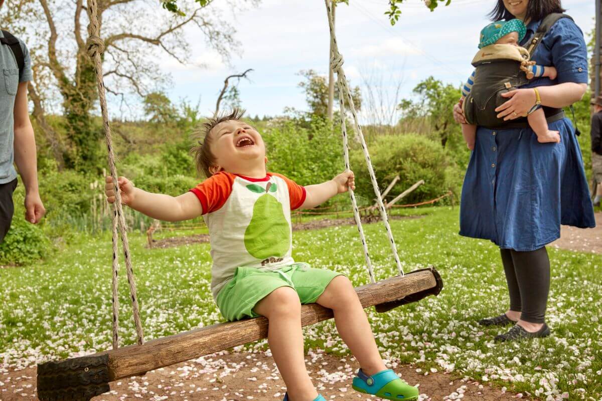 A child laughing on a wooden swing