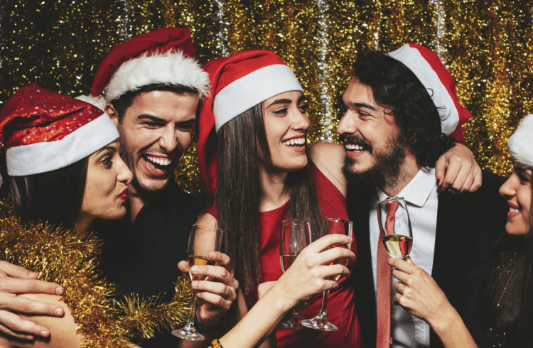 A group of young people wearing Santa hats and holding glasses of wine