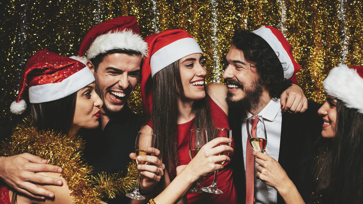 A group of young people wearing Santa hats and holding glasses of wine