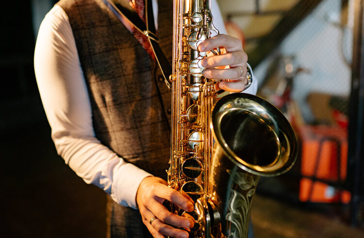 A smartly dressed man playing a saxophone