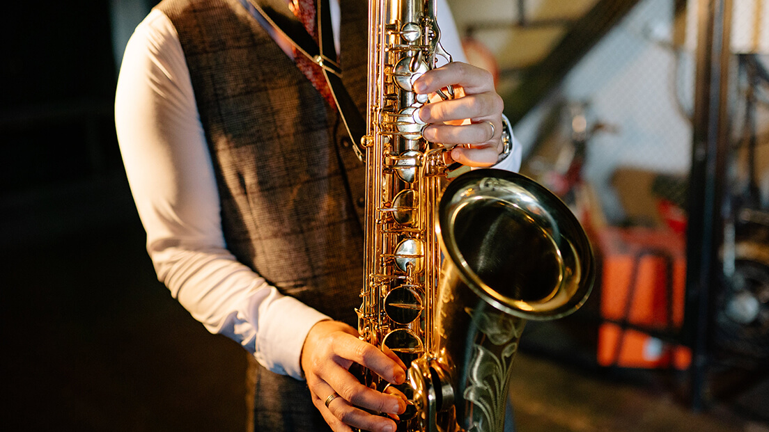 A smartly dressed man playing a saxophone