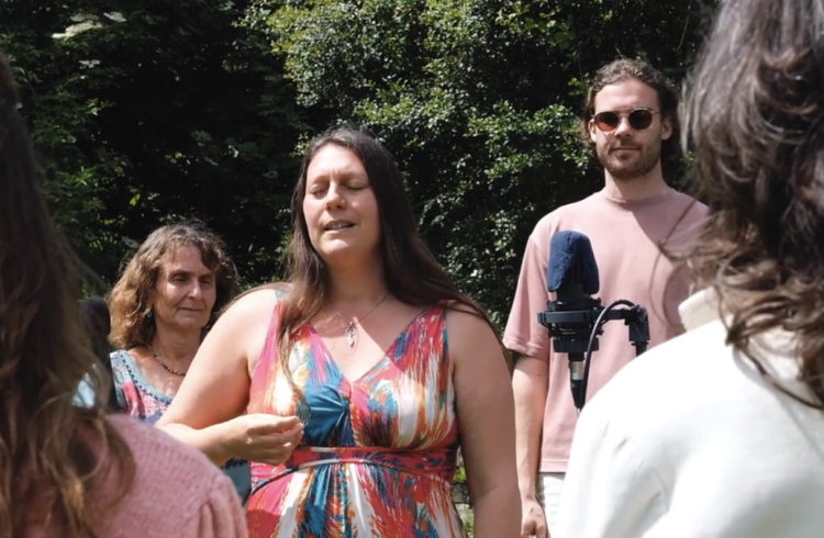 A group of people standing, ready to sing, outdoors near a microphone