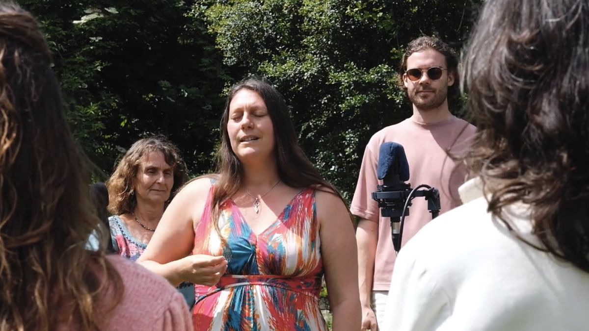 A group of people standing, ready to sing, outdoors near a microphone