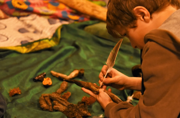 A child crafting using a stick and a feather