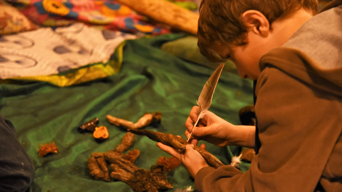 A child crafting using a stick and a feather