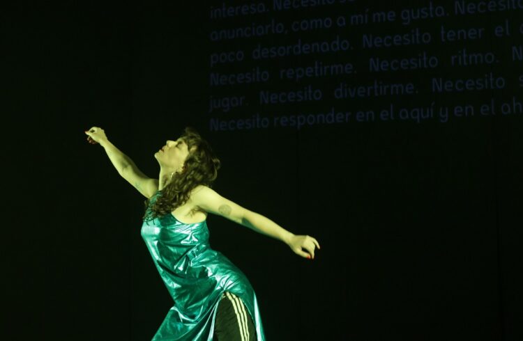 A person wearing a shiny green dress with arms outstretched in opposite directions