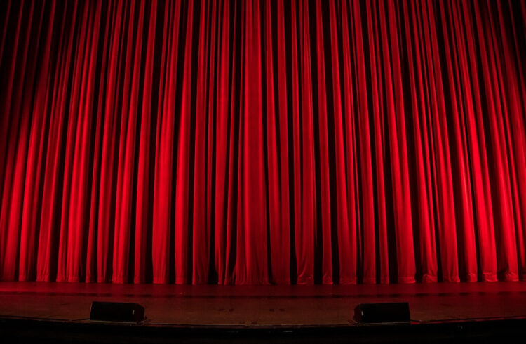 A red curtain across a theatre stage